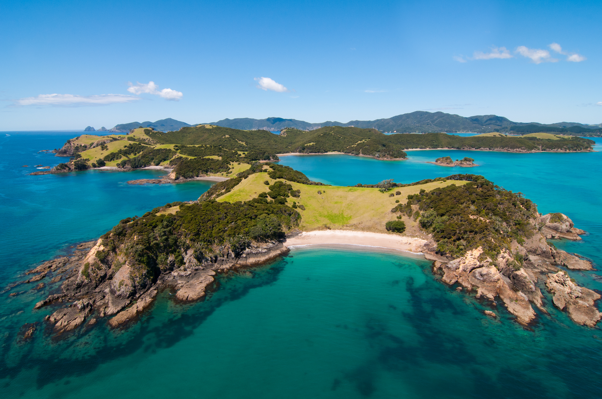 Aerial view of a remote Bay of Islands island with turquoise water and white sand beach