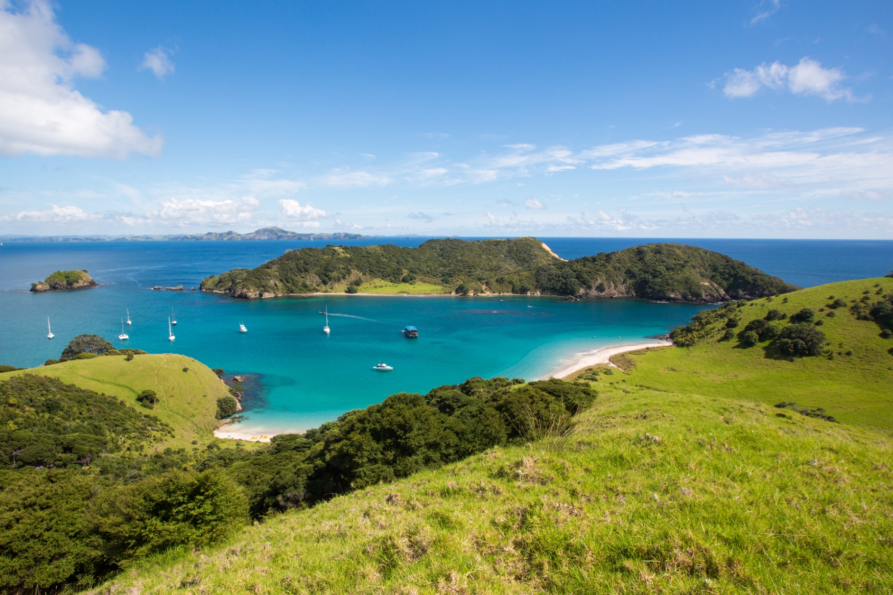 Aerial view of a remote Bay of Islands beach with The Rock anchored nearby